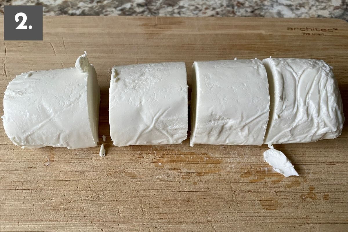 A log of goat cheese cut into 4 equal pieces. There is a number 2 in the top left corner.