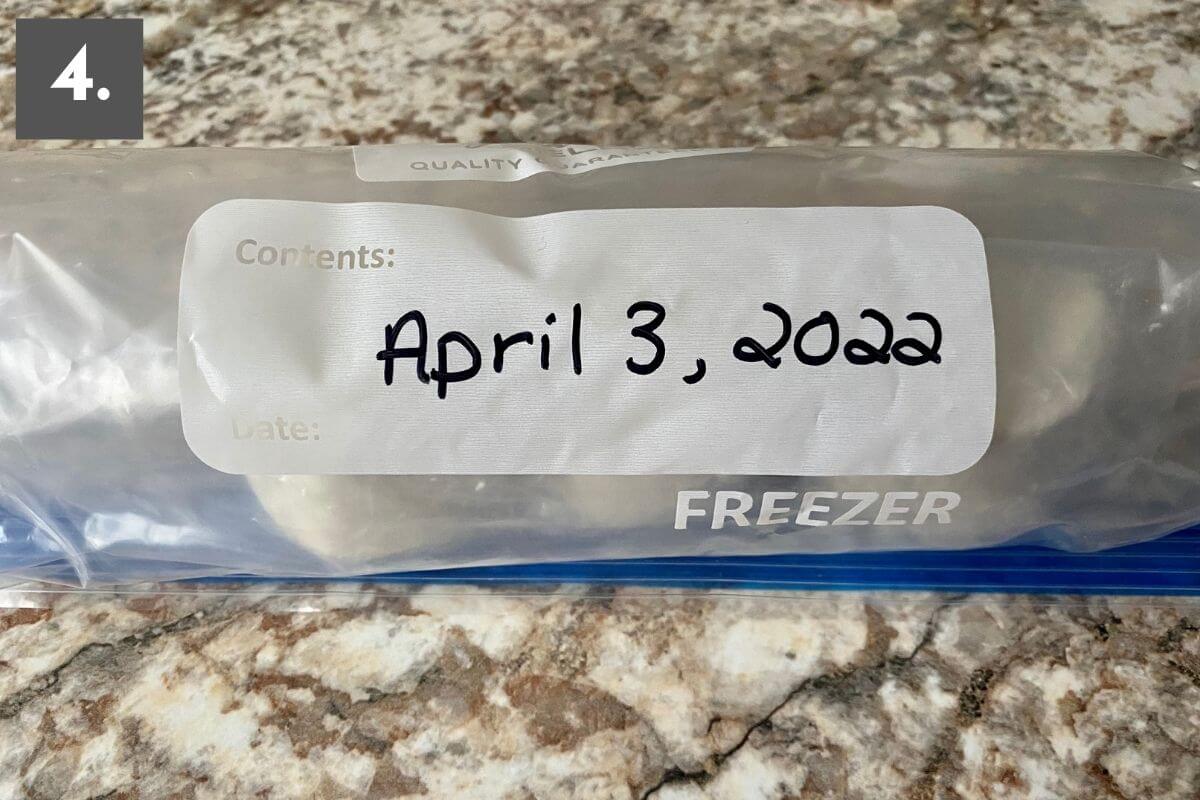 Wrapped goat cheese in a freezer-safe plastic bag with the date April 3, 2022 written in it. There is a number 4 in the top left corner.
