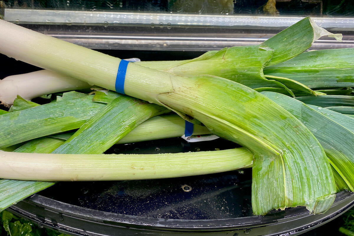 Several leeks on a grocery store shelf.