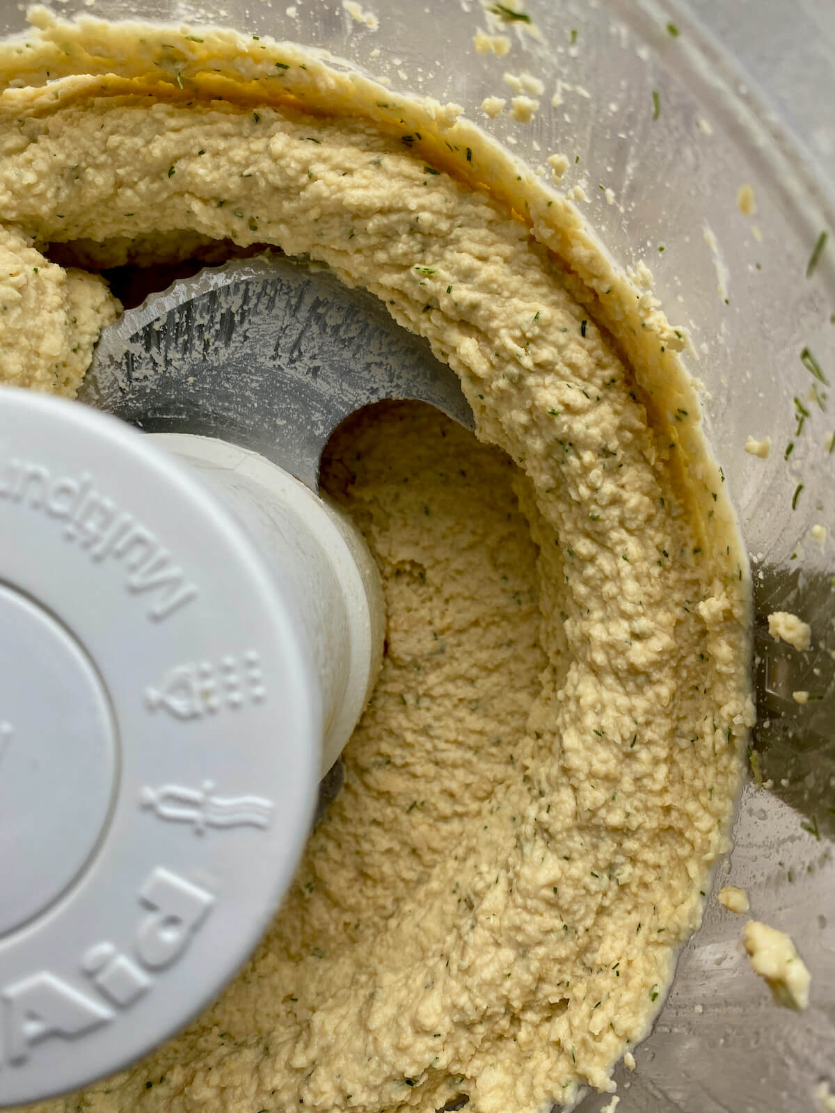 Finished lemon dill hummus in the bowl of a food processor.