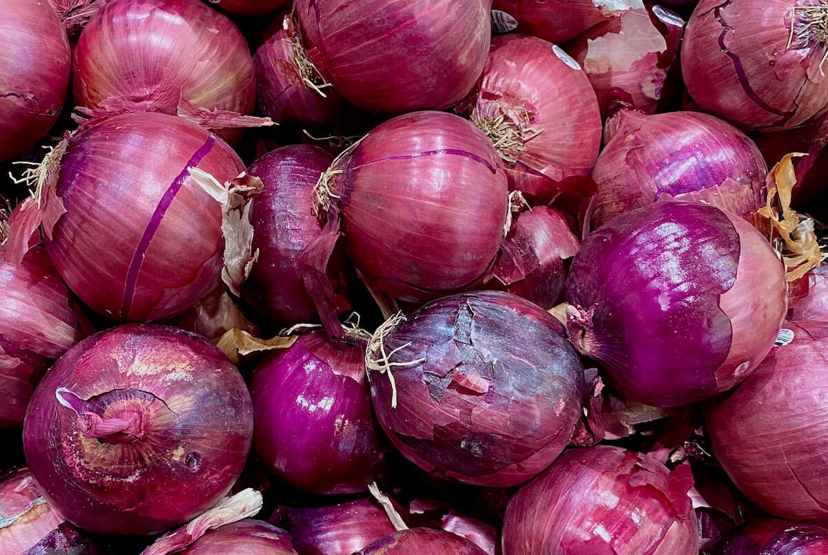A pile of red onions at the grocery store.