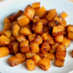 A pile of sautéed butternut squash on a small white plate.