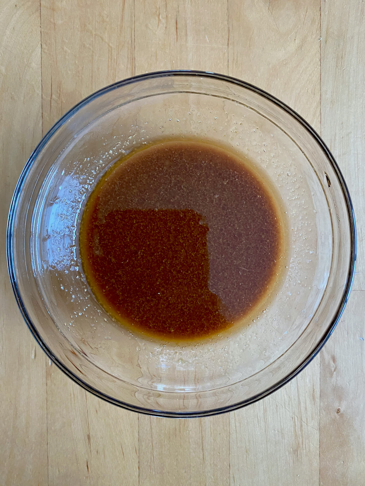 A mixture of cornstarch, soy sauce, sesame oil, and garlic power in a small glass bowl.