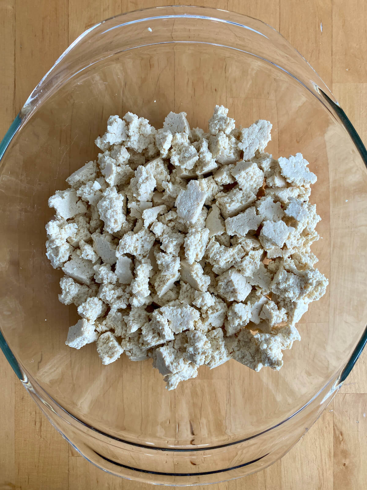 Crumbled tofu in a glass mixing bowl.