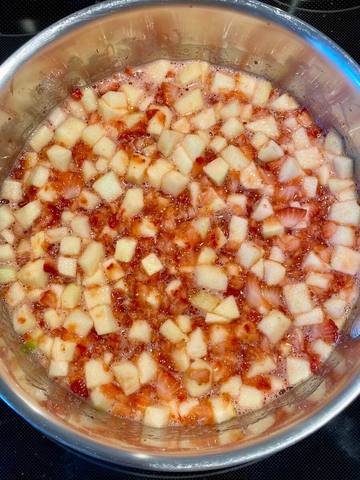 Diced strawberries and apples simmering on the stove.