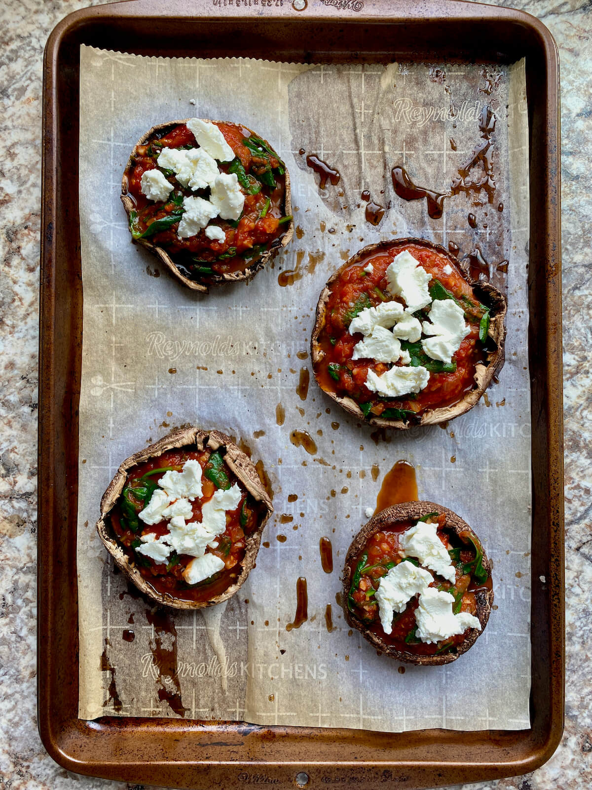 Roasted portobello mushrooms caps topped with spinach tomato sauce and goat cheese.