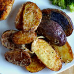 A serving of parmesan-garlic air fryer fingerling potatoes on a white dinner plate.