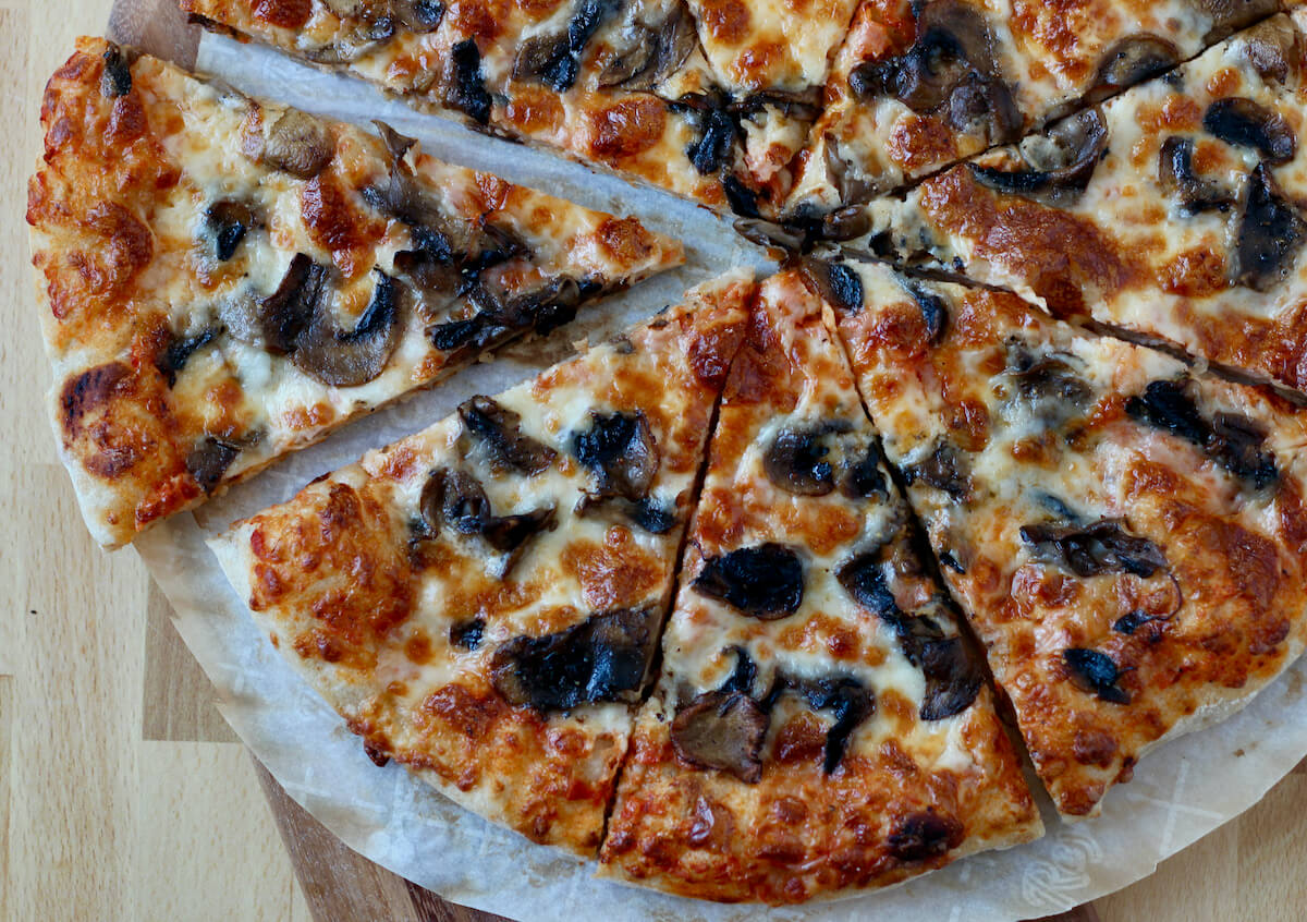 Mushroom pizza cut into 8 slices on a piece of parchment paper.