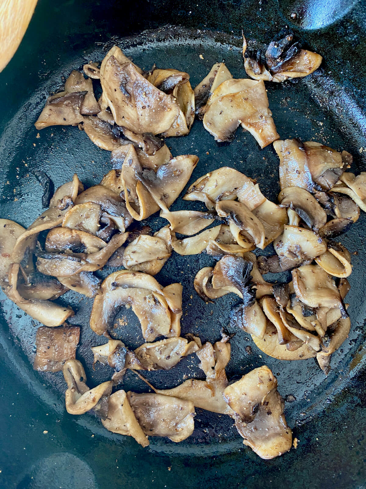 Cooked sliced mushrooms in a cast iron skillet.