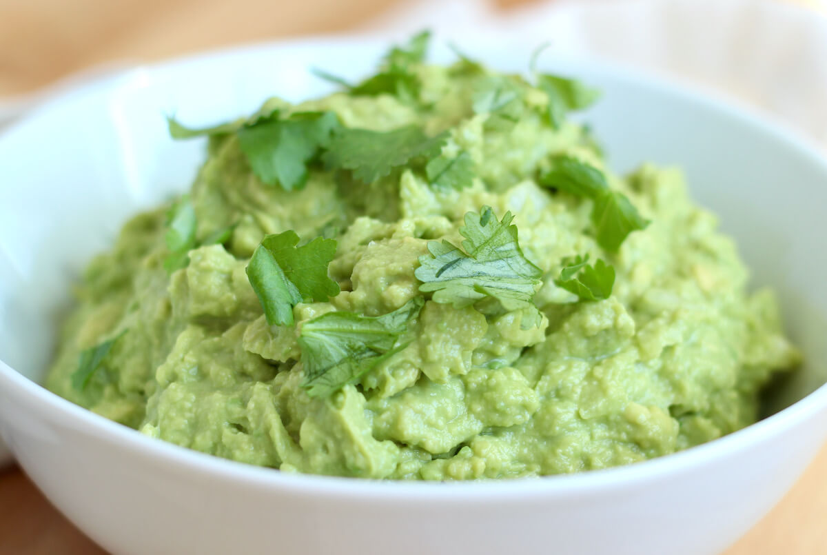 A bowl of guacamole garnished with cilantro.