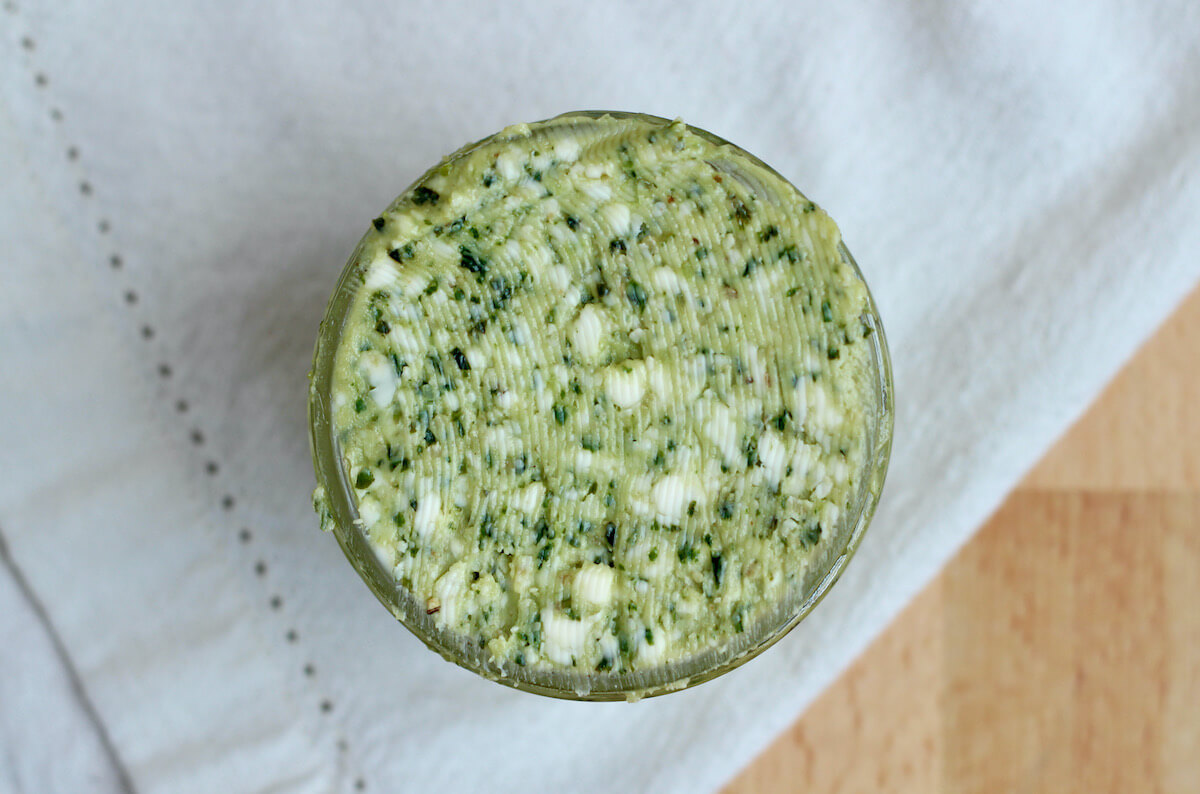 A glass jar filled with basil pesto butter.