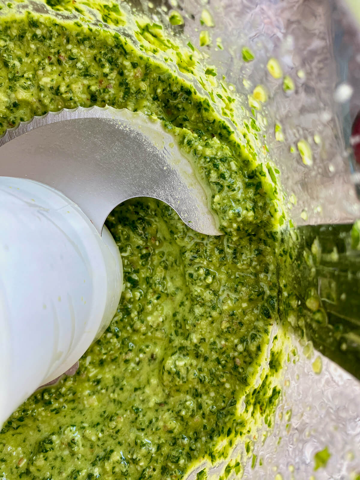 Homemade basil pesto in the bowl of a food processor.