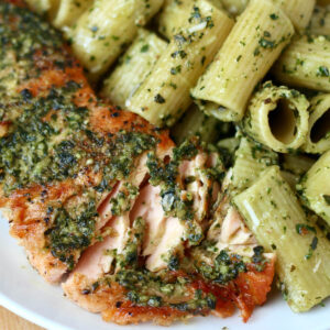 Salmon with pesto butter being served with pesto rigatoni pasta.