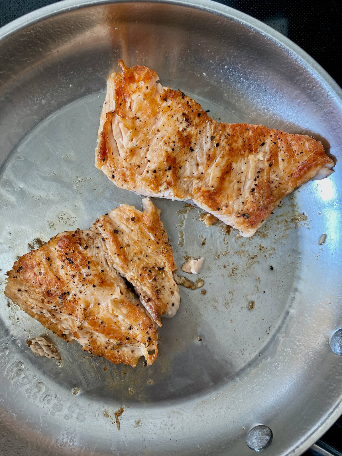 Seared salmon in a stainless steel skillet.