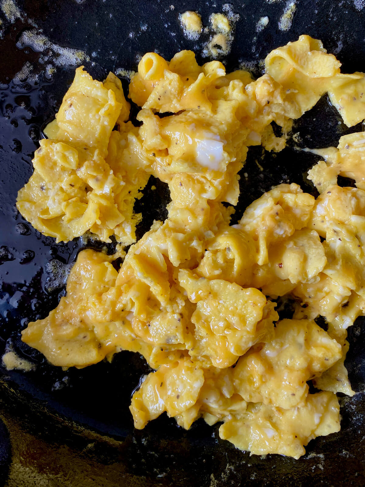 Finished scrambled eggs with cheddar cheese in a cast iron skillet.