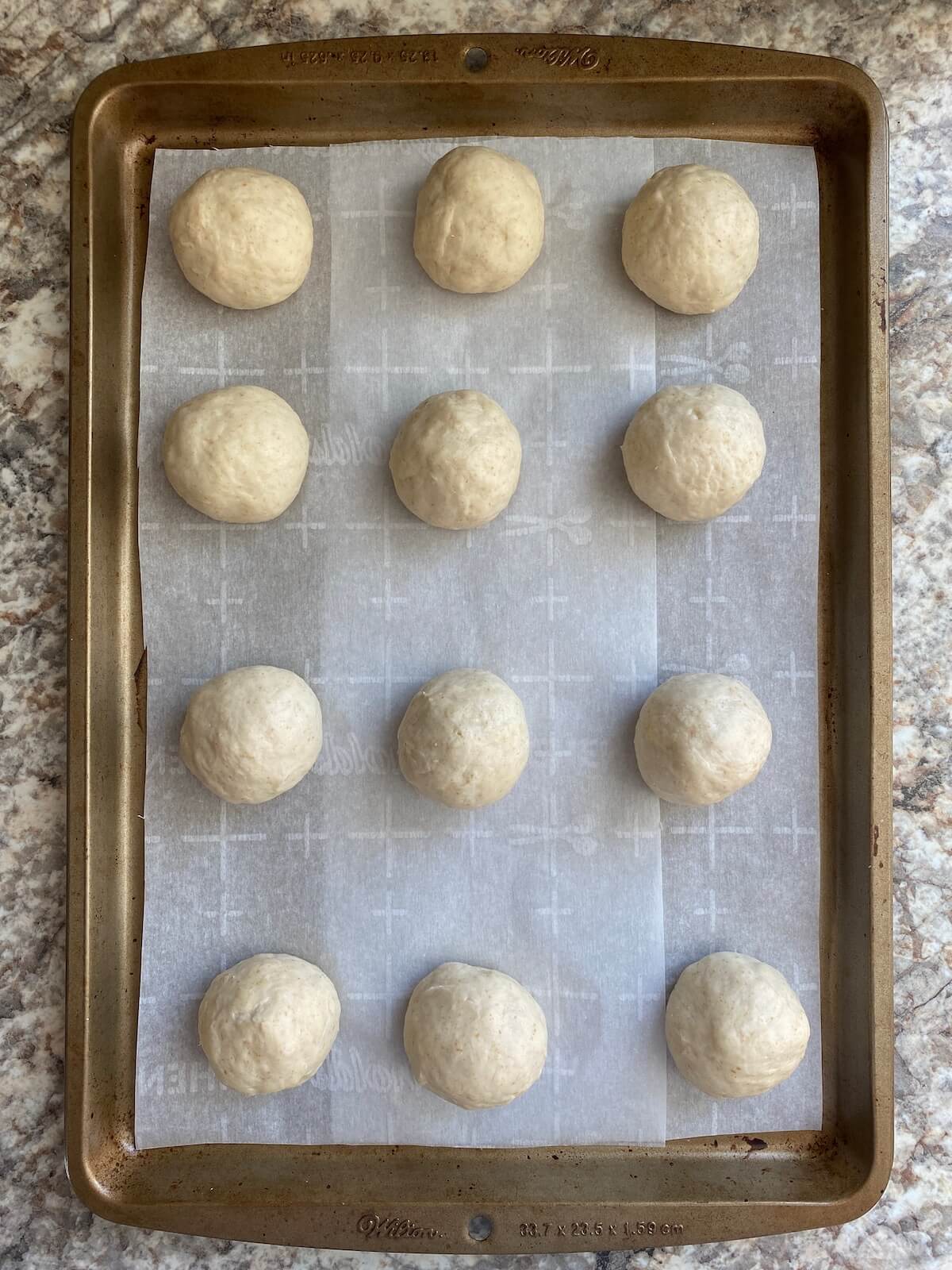 Sourdough tortilla dough balls on a parchment-lined baking sheet.