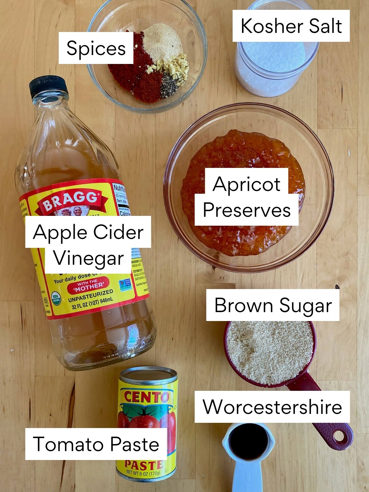 The ingredients to make apricot bbq sauce. Each ingredient is labeled with text. They include spices, kosher salt, apple cider vinegar, apricot preserves, brown sugar, tomato paste, and Worcestershire sauce.
