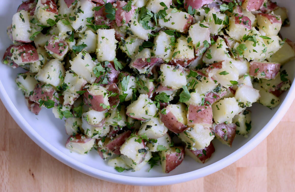 A large serving bowl of herbed potato salad.