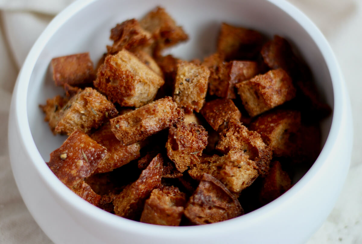 Homemade sourdough croutons in a small white bowl.