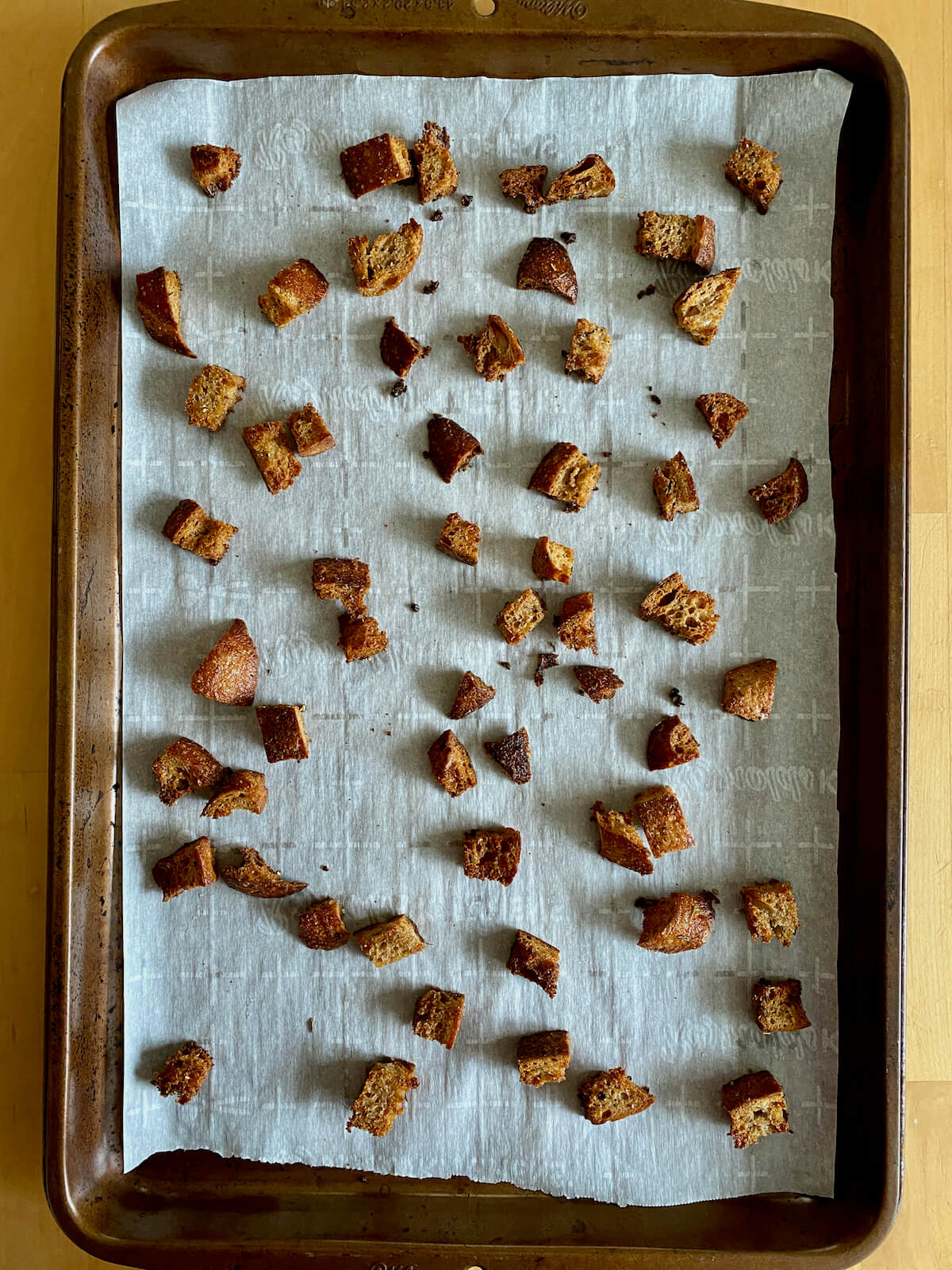 Sourdough croutons on a parchment-lined baking sheet.