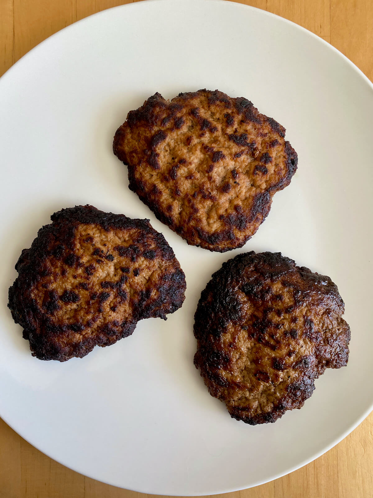 Three cooked turkey smash burgers on a white plate.