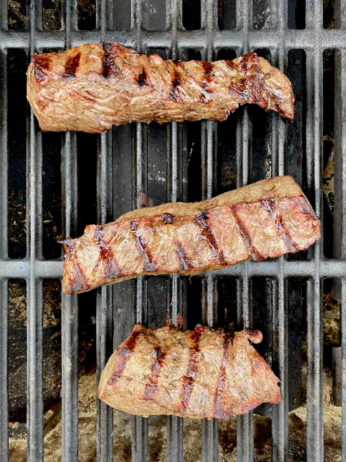 Strips of sirloin steak cooking on a grill.