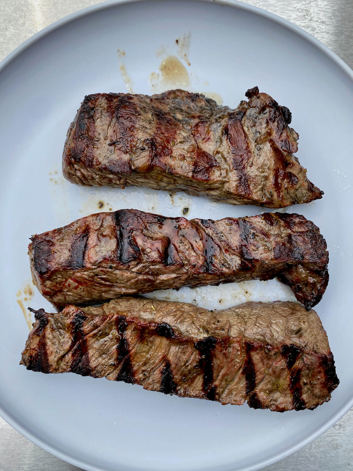 Strips of grilled sirloin steak tips resting on a gray plate.