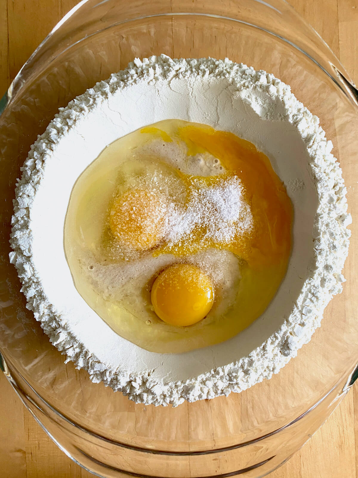 A nest of flour with sourdough discard, eggs, egg yolk, and salt in the middle.