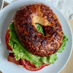 A BLT bagel sandwich on a small white plate.
