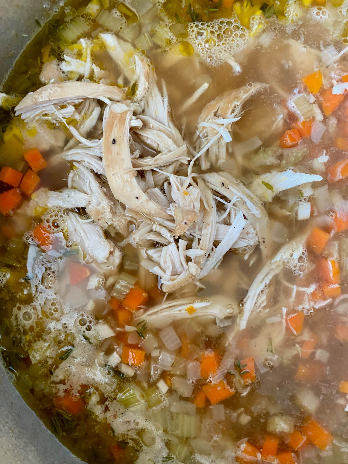 Shredded chicken breast added to the Dutch oven chicken noodle soup.