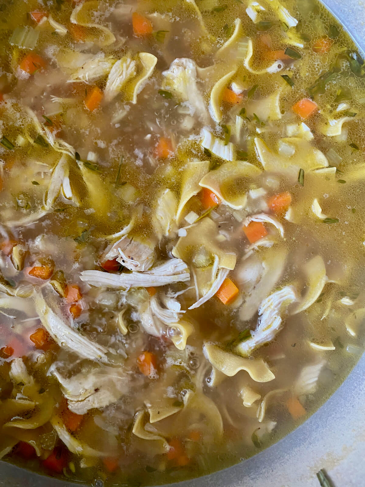 Dry egg noodles added to the simmering chicken soup.