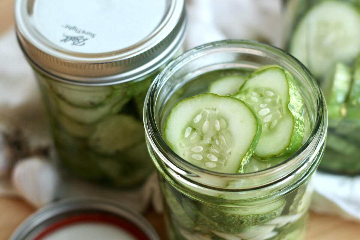 Three jars of refrigerator dill pickles. The front jar is open, showing the pickles.