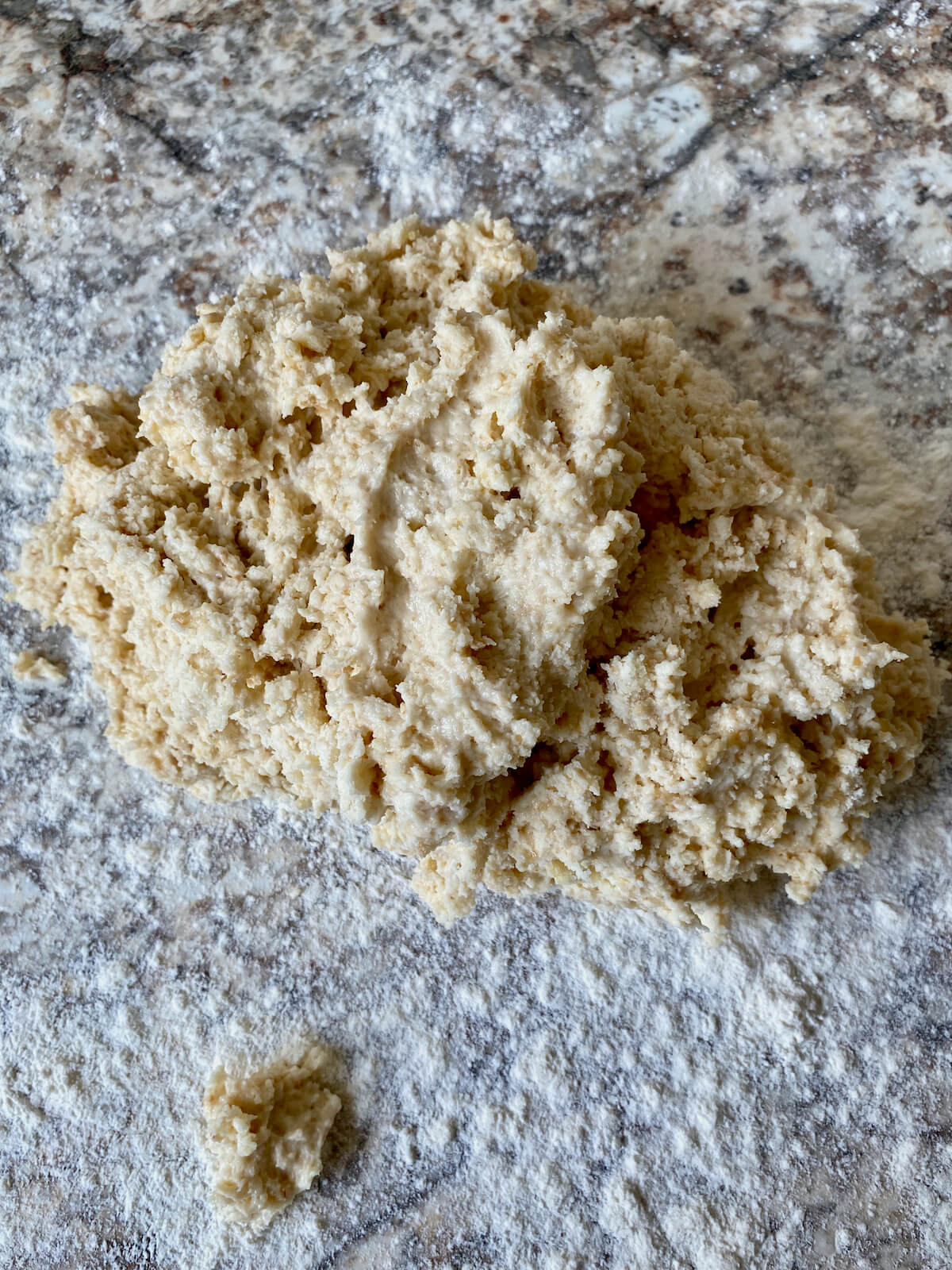 Rough, shaggy biscuit dough on a floured countertop.
