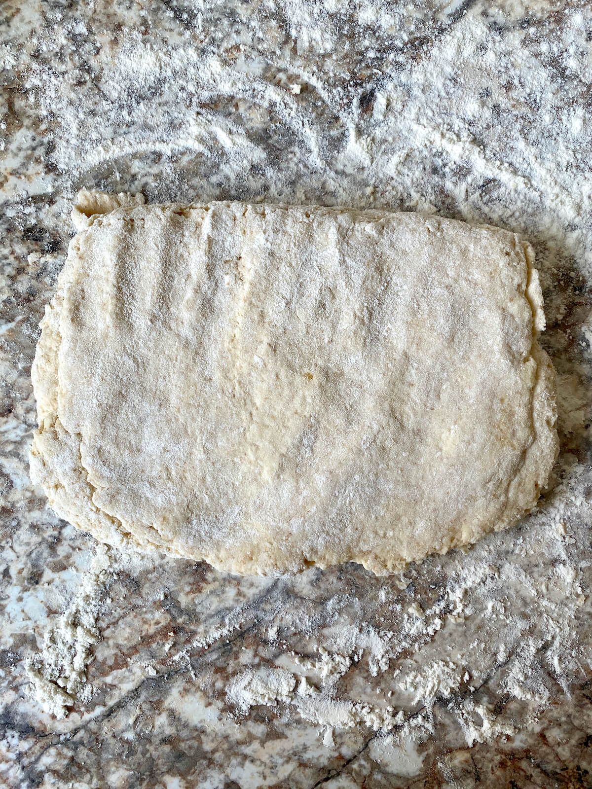 The biscuit dough after being kneaded and pressed into a rectangle on the counter.