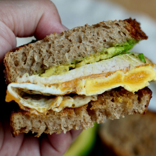 Half of a turkey and egg sandwich being held up to the camera to show the cross section.