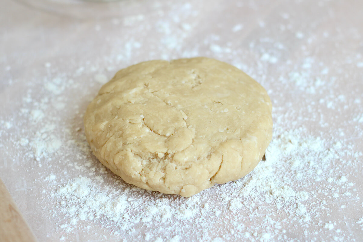 A disk of pie dough on a lightly floured surface.