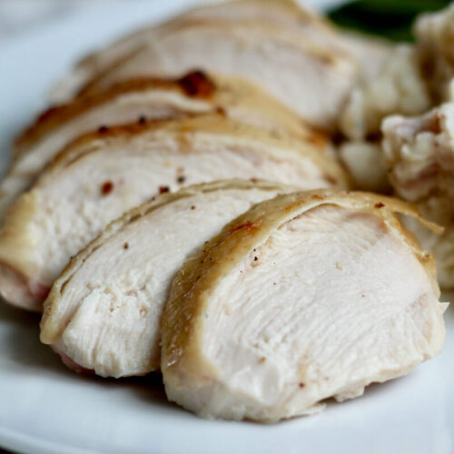 Slices of dry brined chicken on a dinner plate.