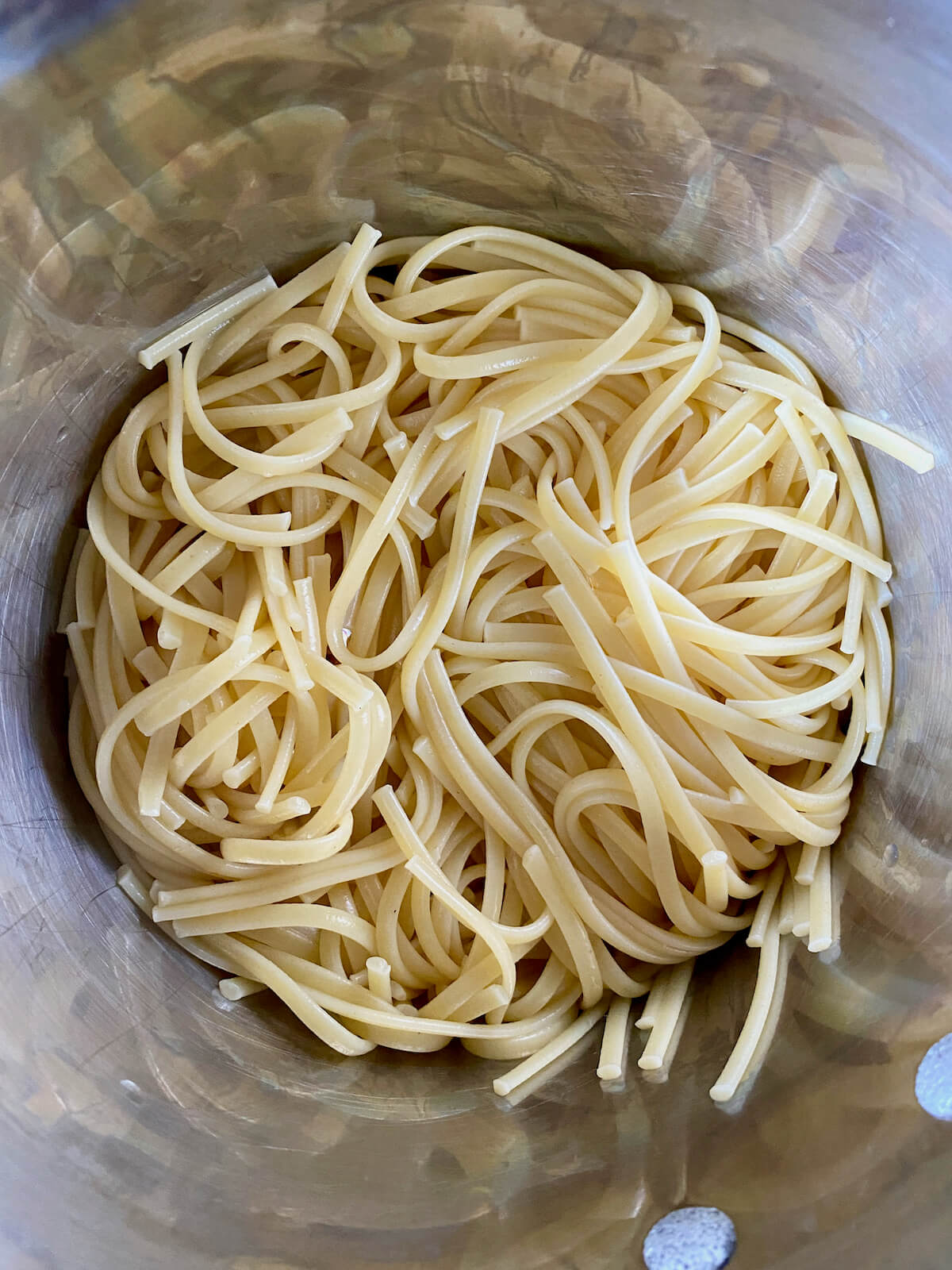 Cooked linguine in a stainless steel pot.