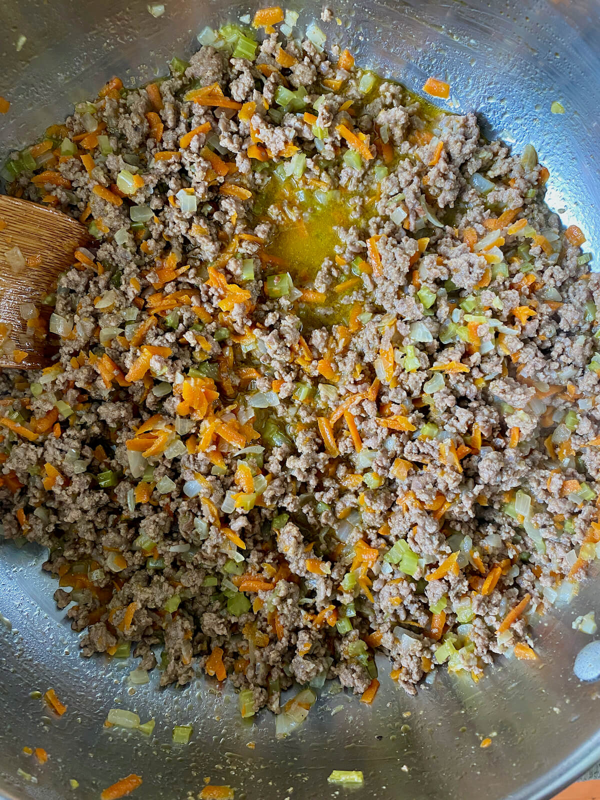 The ground beef and vegetables in a stainless steel pot after simmering in white wine.