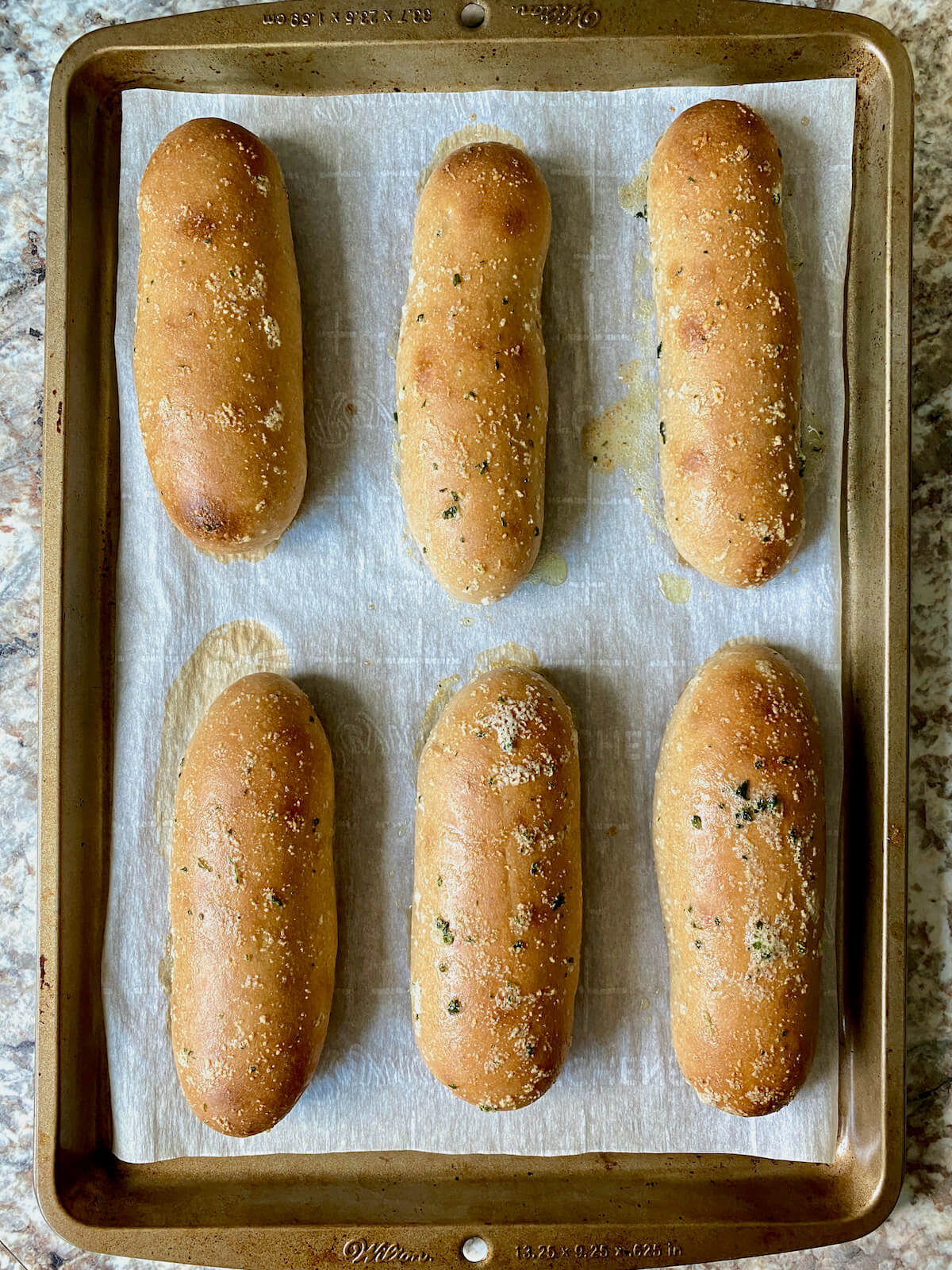 Baked sourdough breadsticks brushed with garlic butter on a parchment-lined baking sheet.