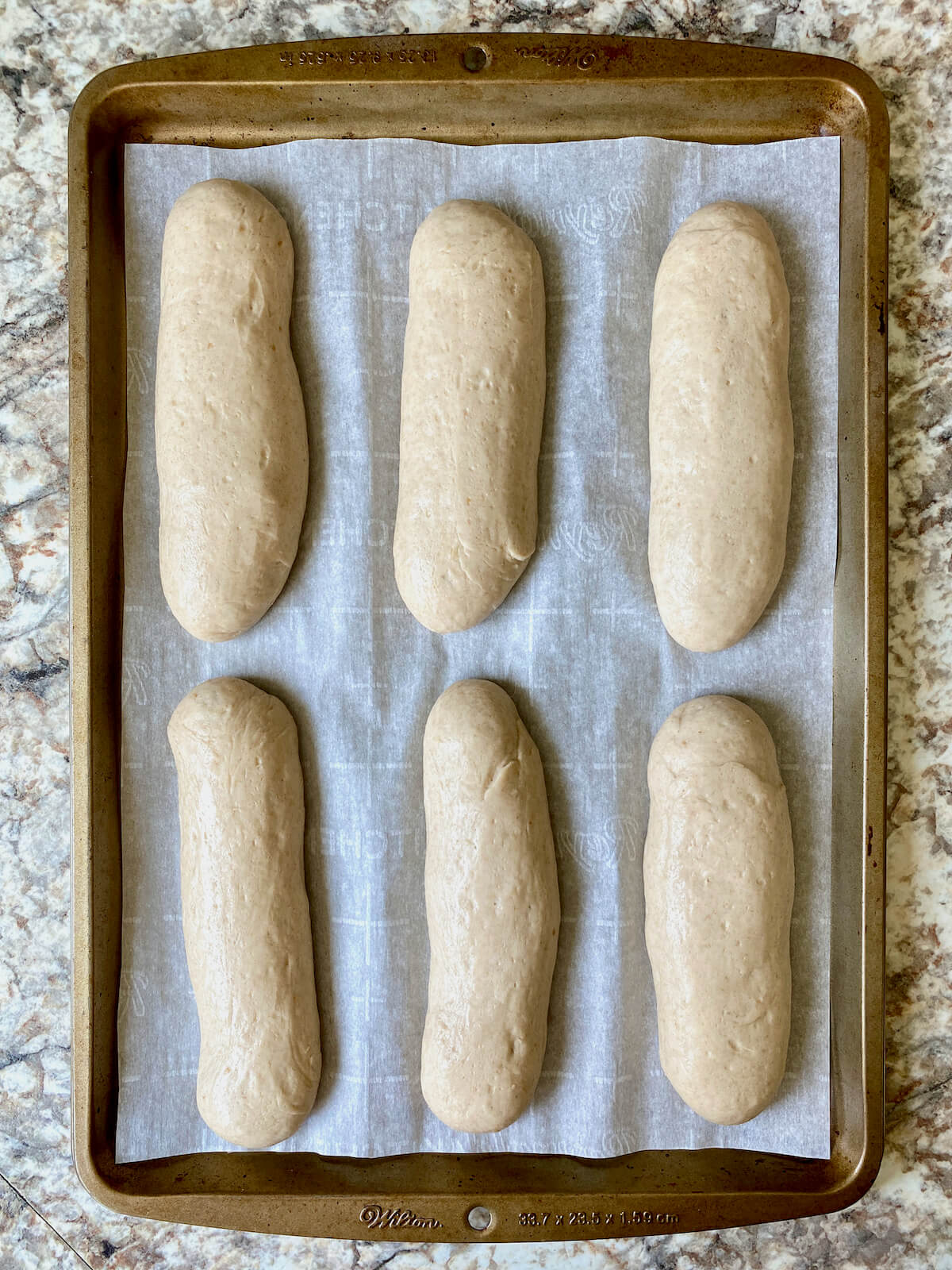 Unbaked sourdough breadsticks on a baking sheet after proofing.