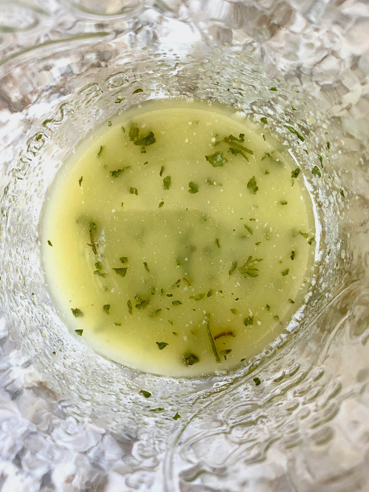 Melted butter, dried herbs, salt, and garlic powder mixed together in a glass jar.
