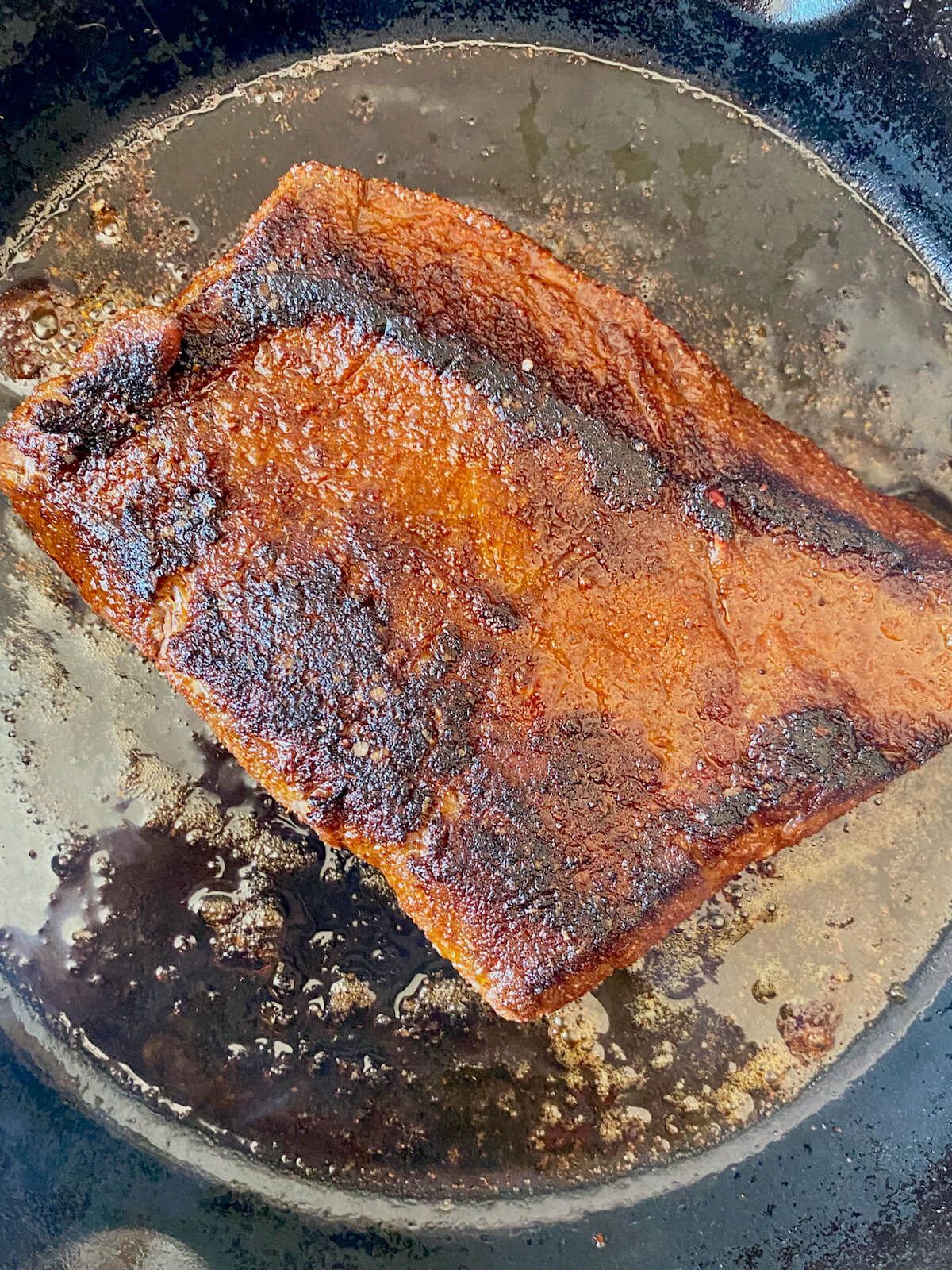 A piece of seared steak in a cast iron skillet.