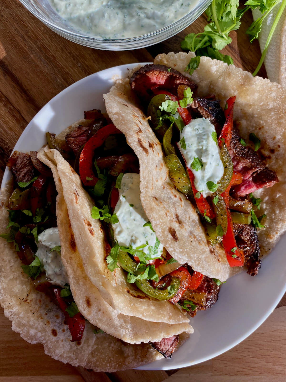 Three beef fajita tacos on a small white plate.