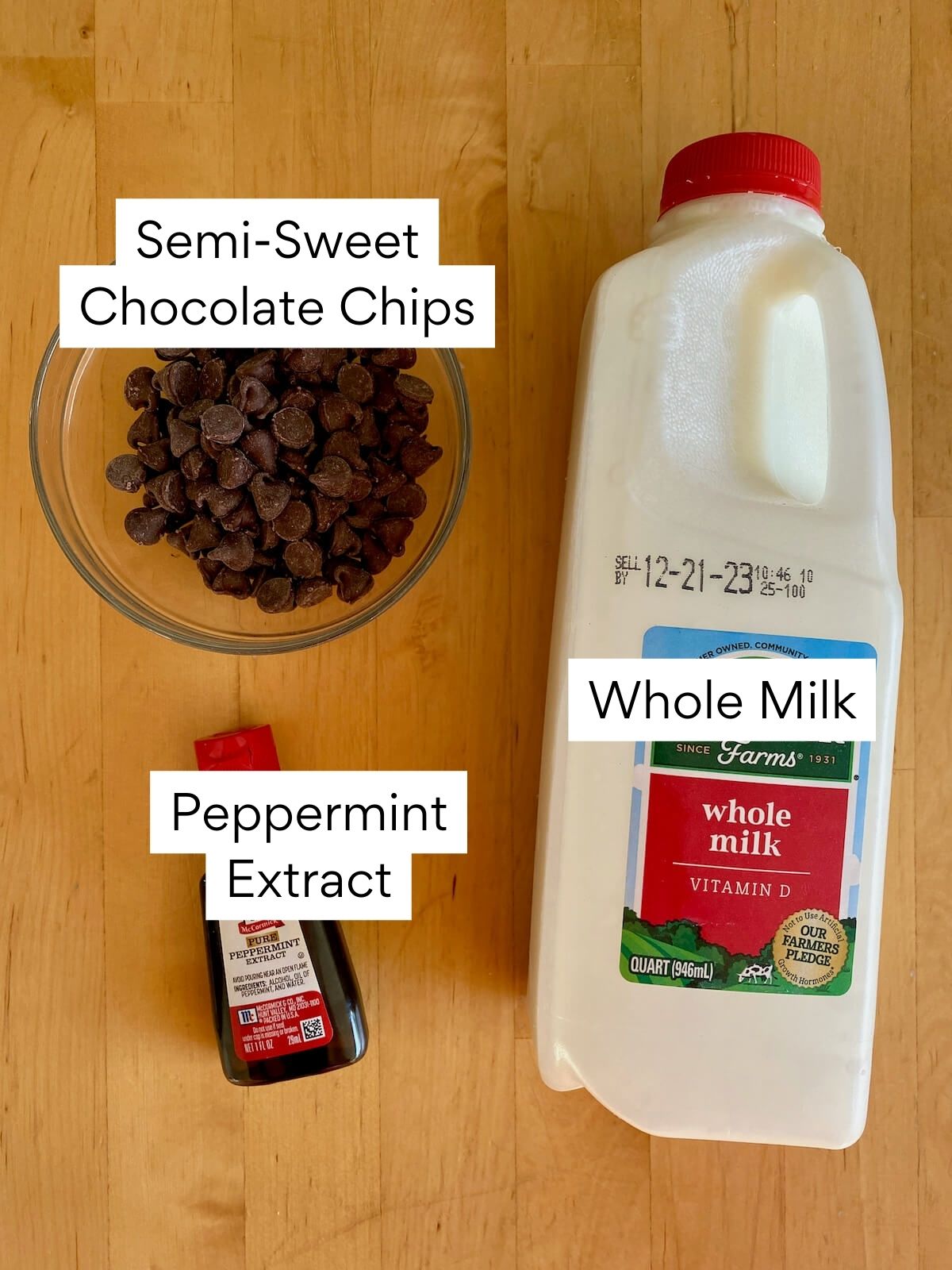 The ingredients to make peppermint hot chocolate. Each ingredient is labeled with text. They include semi-sweet chocolate chips, peppermint extract, and whole milk.