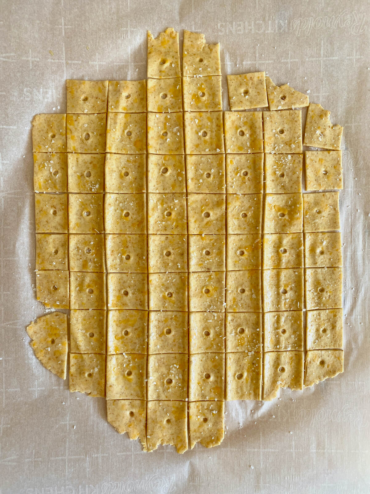 Sourdough discard cheese crackers cut into squares with a hole poked in the middle of each.