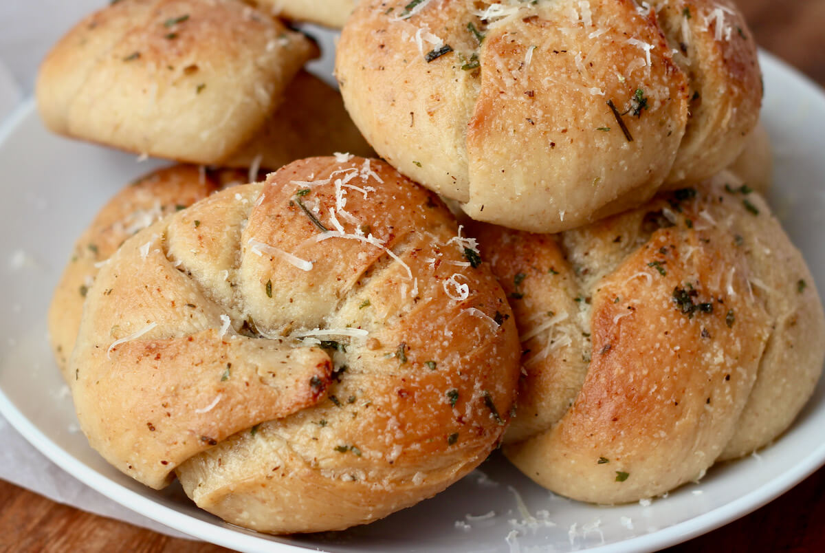 Sourdough garlic knots garnished with grated parmesan cheese on a small plate.