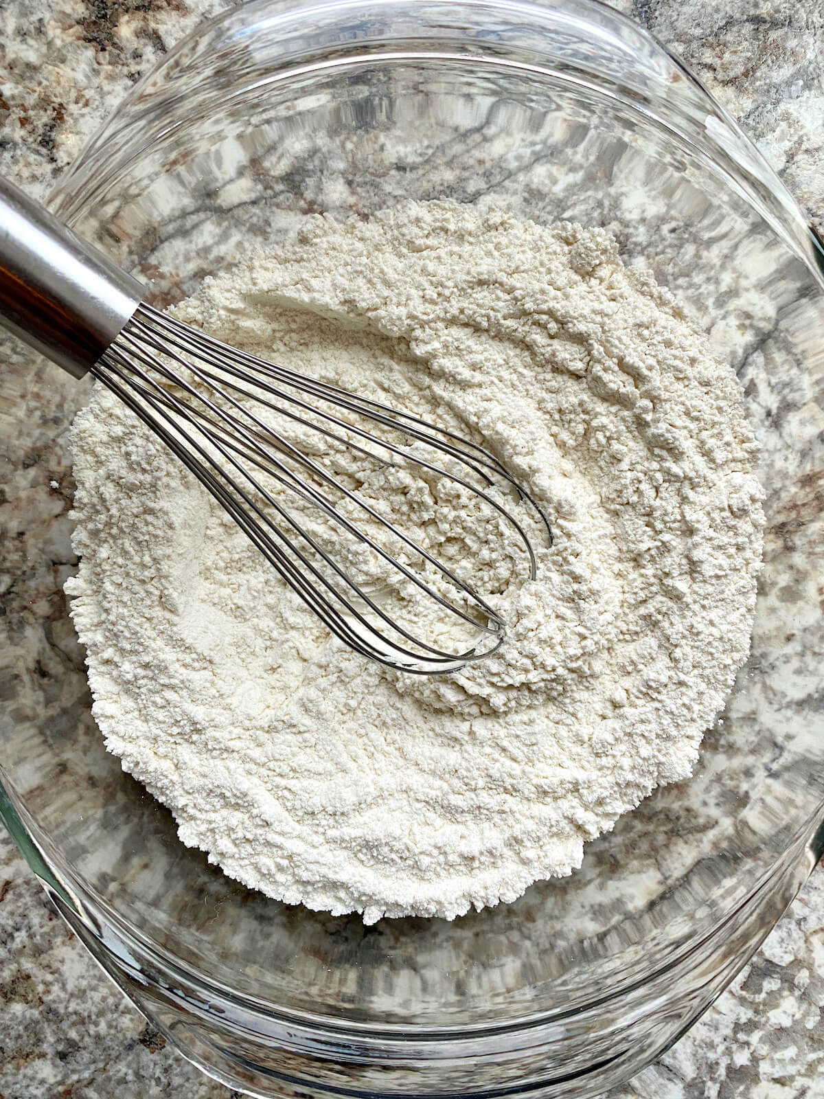 Flour, baking soda, and salt whisked together in a glass mixing bowl.