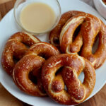 A plate of sourdough soft pretzels with honey mustard dipping sauce.
