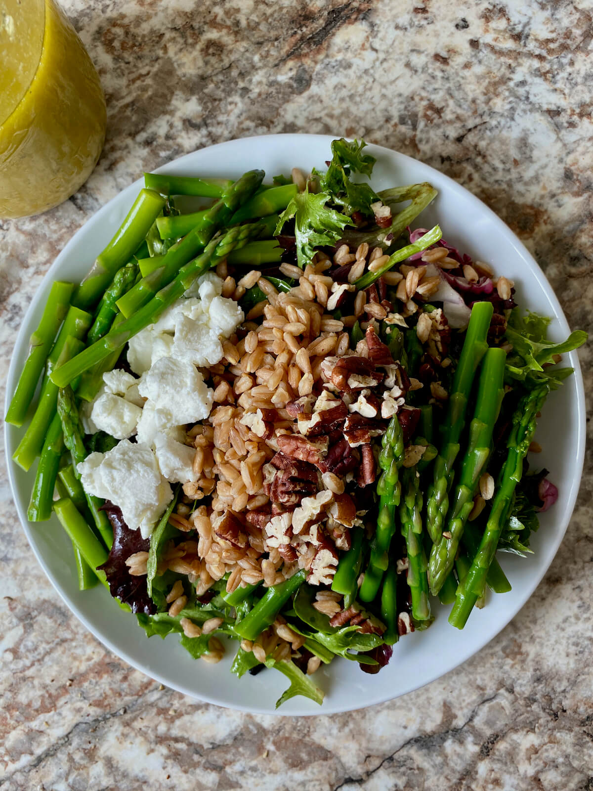 A small plate of asparagus, goat cheese, and farro salad with lemon vinaigrette.